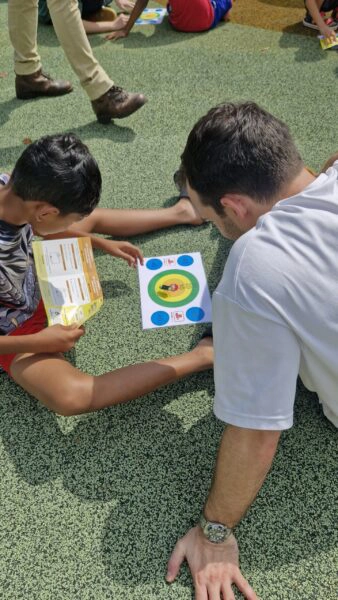 Youths participating in a hands-on engineering session with DLE volunteers, exploring electrical connections and competing in a solar grasshopper challenge.
